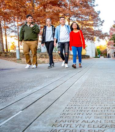 Four students walking on senior walk in fall season